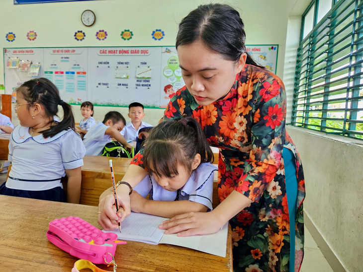 Cô giáo trên đảo Trí Nguyên cầm tay học sinh viết những nét chữ đầu tiên - Ảnh: MINH CHIẾN