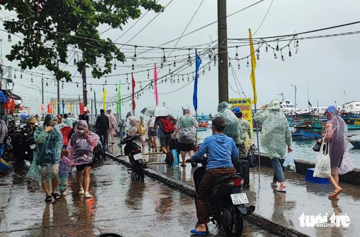 Hay tin tàu cao tốc chạy lại nhiều khách du lịch kẹt lại ở đảo Nam Du đã mặc áo mưa tranh thủ xuống tàu về lại đất liền - Ảnh: LÝ LỢI