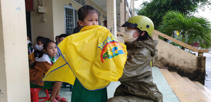 Chị Trần Diễm My cùng con vượt mưa hơn 4 km để kịp giờ khai giảng - Ảnh: THANH HUYỀN