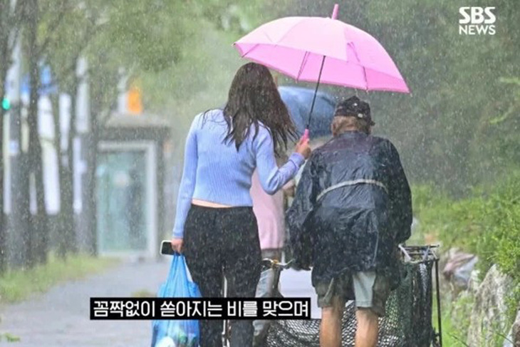 Cô gái trẻ chịu ướt để nhường ô che mưa cho cụ ông.