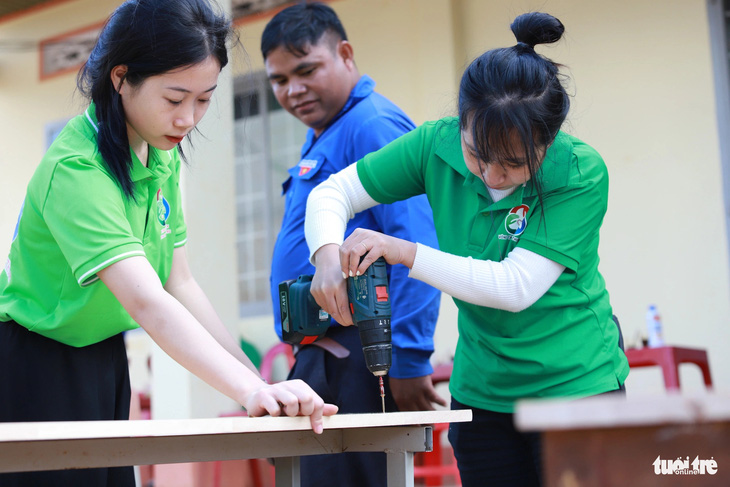 Nhiều tình nguyện viên là học sinh cũng làm thợ sửa bàn ghế cho học sinh - Ảnh: MINH PHƯƠNG