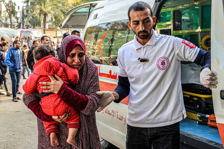 Nhân viên y tế hỗ trợ người phụ nữ bế con đến Bệnh viện Châu Âu ở Khan Yunis, phía nam Dải Gaza, ngày 31-12-2023 - Ảnh: AFP