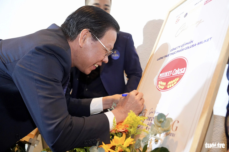Chủ tịch UBND TP.HCM Phan Văn Mãi ký tên vào biểu trưng logo của doanh nghiệp đạt giải - Ảnh: HỮU HẠNH