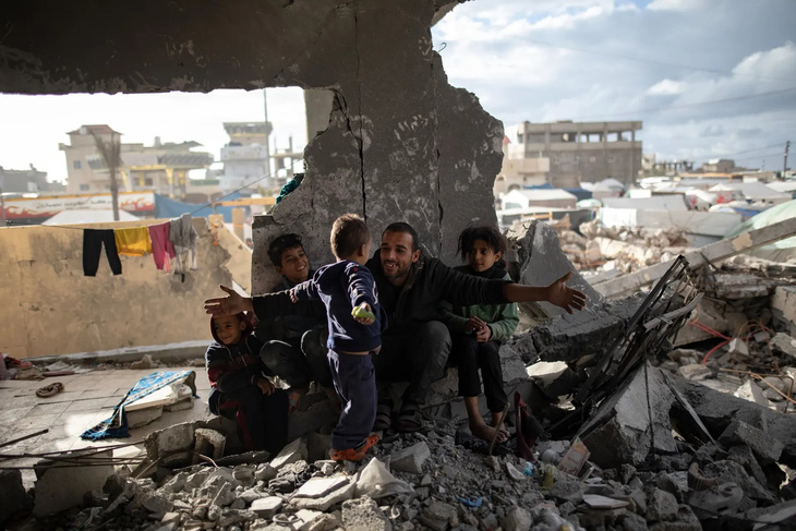 Anh Muhammad Al-Durra, một người Palestine, nói chuyện với một trong số các con anh khi họ đang trú tạm trong một ngôi nhà đổ nát ở Rafah, Gaza. Mấy cha con đã lang thang khắp nơi kể từ ngày 11-10 sau khi nhà họ bị trúng bom và mẹ của bọn trẻ đã thiệt mạng - Ảnh: EPA