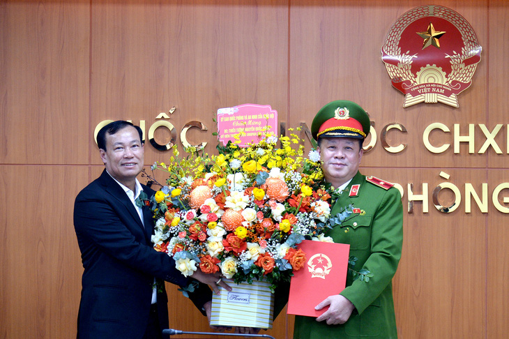 Chủ nhiệm Ủy ban Quốc phòng và An ninh, Trung tướng Lê Tấn Tới (trái) trao nghị quyết và tặng hoa chúc mừng ủy viên thường trực Ủy ban Quốc phòng và An ninh Nguyễn Quốc Hùng - Ảnh: GIA HÂN