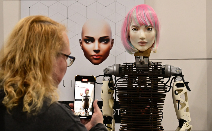 Một phụ nữ chụp ảnh cùng mô hình robot AI ở Hội chợ điện tử tiêu dùng (CES) tại thành phố Las Vegas (Mỹ) ngày 10-1 - Ảnh: AFP