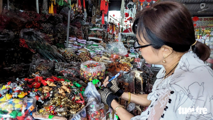 Một tiểu thương ở chợ Đông Ba thực hiện việc niêm yết giá lên mặt hàng móc khóa, đồ lưu niệm - Ảnh: NHẬT LINH