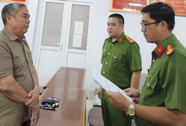 Công an tống đạt quyết định khởi tố bị can đối với ông Trần Xuân Hiền - phó giám đốc Công ty TNHH tư vấn Việt Hà - Ảnh: Công an cung cấp