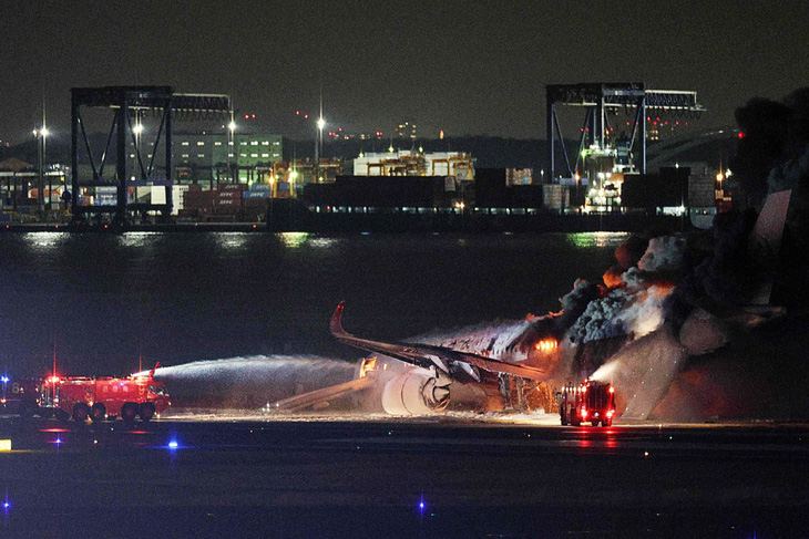 Nhiều xe cứu hỏa đã được điều đến dập lửa bao trùm chiếc máy bay chở khách bốc cháy ở sân bay Haneda, Nhật Bản, ngày 2-1 - Ảnh: AFP