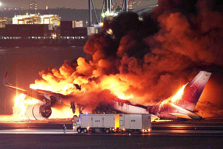 Ngọn lửa bao trùm chiếc máy bay chở khách của Japan Airlines sau va chạm ở sân bay Haneda, Tokyo, ngày 2-1 - Ảnh: AFP