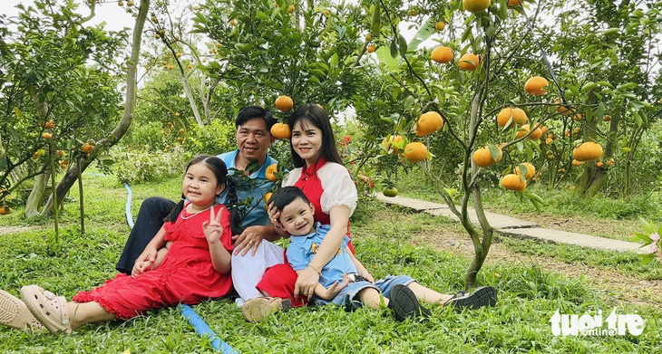 A family takes souvenir photos at Hai Kiet tangerine garden - Photo: DANG TUYET
