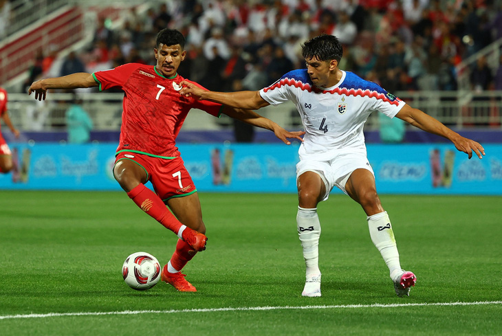 Cầu thủ Thái Lan (áo trắng) tranh chấp bóng với Oman - Ảnh: REUTERS
