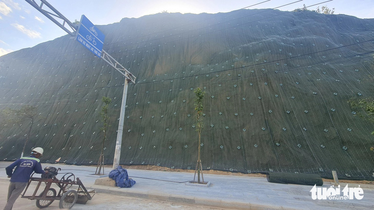Các công nhân đã dùng lưới thép chịu lực cao phủ lên bề mặt núi Bà Hỏa và khoan đóng cọc cố định để chống sạt lở một đoạn dài núi này - Ảnh: LÂM THIÊN