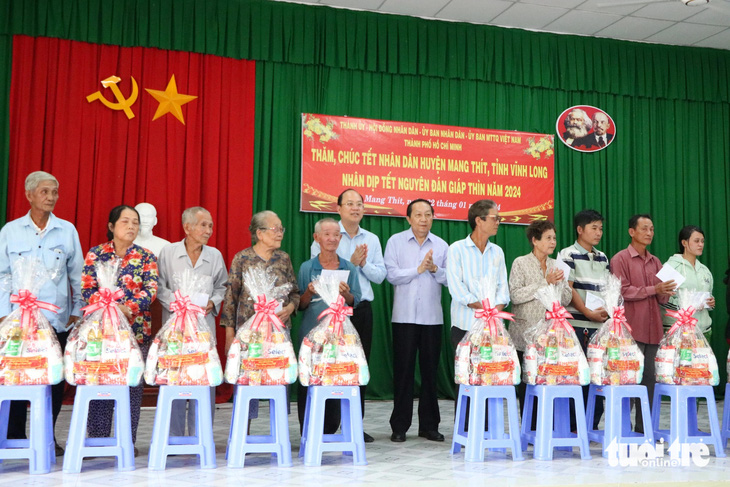 Phó bí thư thường trực Thành ủy TP.HCM Nguyễn Hồ Hải (ở giữa, bên trái) tặng quà Tết cho các hộ dân khó khăn huyện Mang Thít - Ảnh: CẨM NƯƠNG