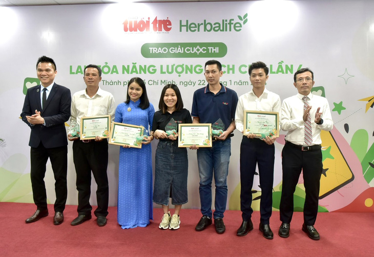 Giám đốc truyền thông Herbalife VN Nguyễn Thành Đạt (bìa trái) và Phó tổng biên tập báo Tuổi Trẻ Trần Xuân Toàn (bìa phải) trao giải nhất, nhì, ba cuộc thi cho các tác giả - Ảnh: T.T.D.