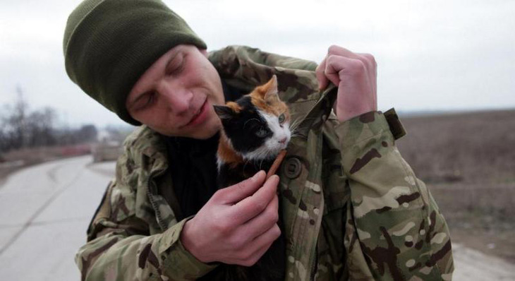 Một quân nhân Ukraine ôm một con mèo khi canh gác tại một trạm kiểm soát gần thành phố cảng Mariupol - Ảnh: FILIPPOV