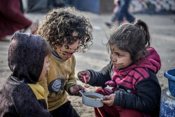 Trẻ em Palestine ở Rafah, Dải Gaza ăn bữa ăn ấm ít ỏi giữa cuộc sống khó khăn tại đây - Ảnh: Anadolu