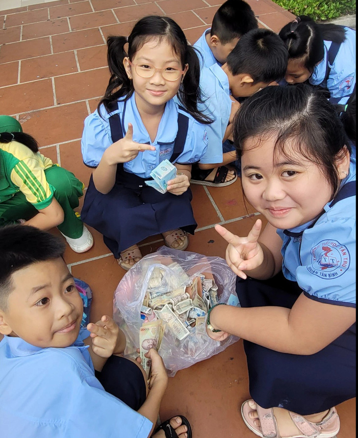 Học sinh lớp 1 Trường tiểu học Tân Trụ hào hứng tham gia hội thu heo đất tặng quà Tết cho học sinh nghèo - Ảnh: SONG KHUÊ