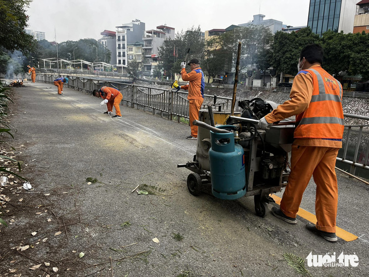 Công nhân kẻ lại vạch sơn đường, dọn dẹp tuyến đường dọc sông Tô Lịch để dành riêng cho xe đạp - Ảnh: QUANG VIỄN