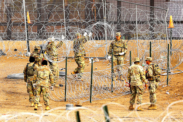 Các thành viên Lực lượng vệ binh quốc gia bang Texas dựng hàng rào thép gai ở khu vực biên giới Mỹ - Mexico để ngăn người nhập cư trái phép vào hôm 23-1 - Ảnh: REUTERS