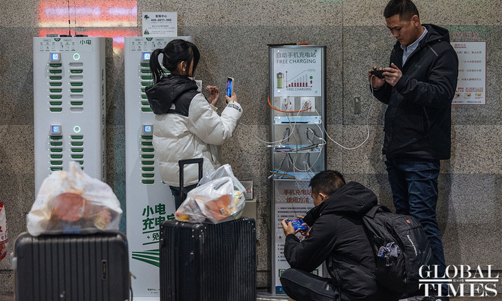 Một số người tranh thủ sạc đầy pin điện thoại trước cuộc hành trình có thể kéo dài đến nhiều giờ đồng hồ trên tàu - Ảnh: GLOBAL TIMES