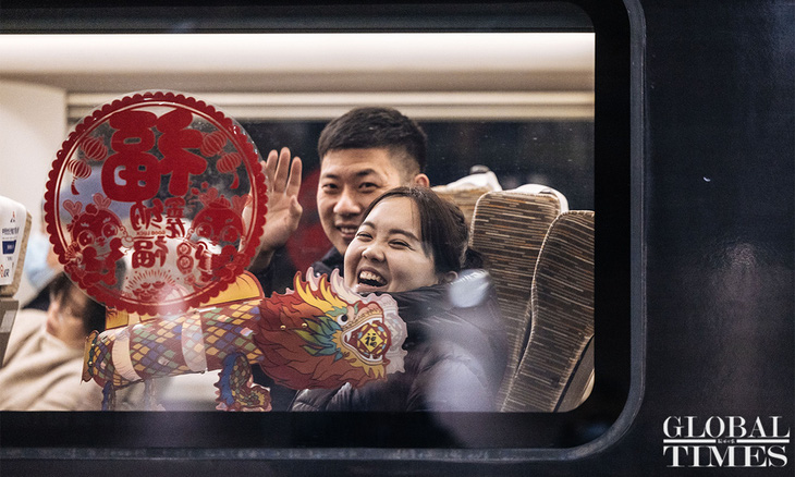 Hai hành khánh vui vẻ vẫy tay với ống kính trước giờ tàu khởi hành - Ảnh: GLOBAL TIMES