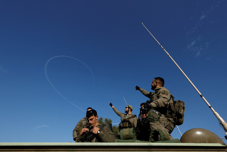 Binh sĩ Israel chỉ về phía dấu vết trên bầu trời khi cuộc xung đột tiếp diễn giữa Israel và Hamas gần biên giới với Dải Gaza, ngày 22-1 - Ảnh: REUTERS