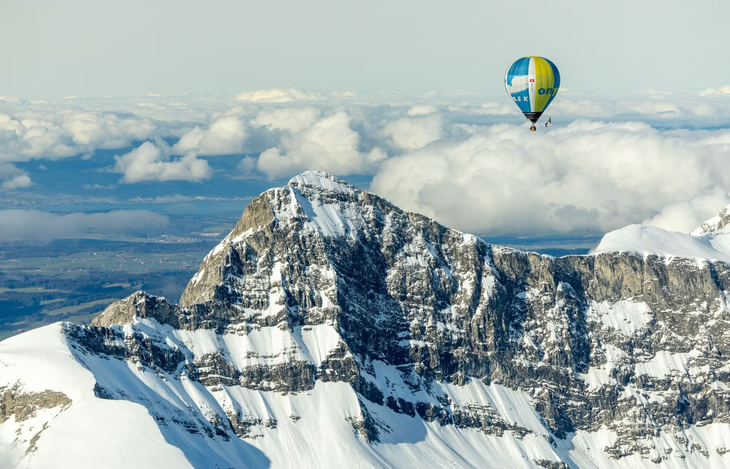 Một khinh khí cầu thoắt ẩn thoắt hiện bên trong những đám mây trên dãy núi Alps, vốn được bao phủ bởi tuyết trắng xóa quanh năm - Ảnh: REUTERS