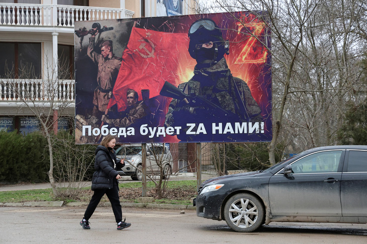 Một người phụ nữ đi ngang qua biểu ngữ ca ngợi các lực lượng vũ trang Liên Xô và Nga tại khu định cư Chernomorskoye, Crimea, ngày 25-1 - Ảnh: REUTERS