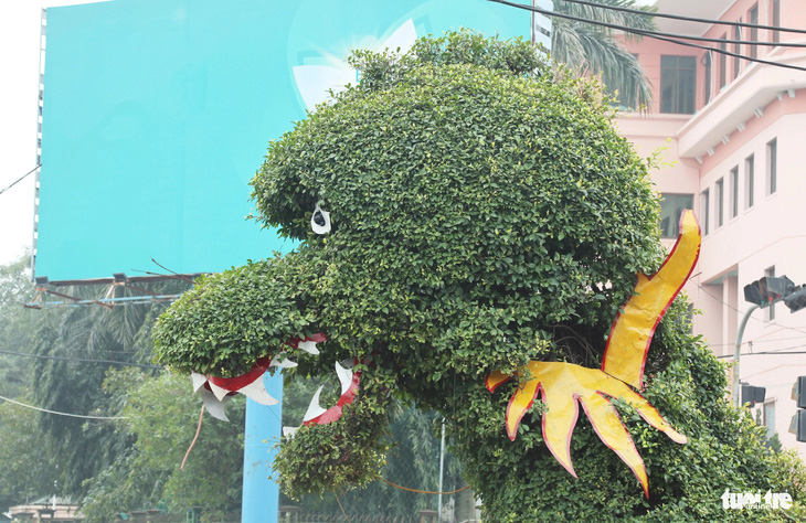 Nhân viên cây xanh cắt tỉa cành lá, trang trí lại các bộ phận mắt, miệng cho hai con rồng được tạo hình bằng cây gừa - Ảnh: DOÃN HÒA