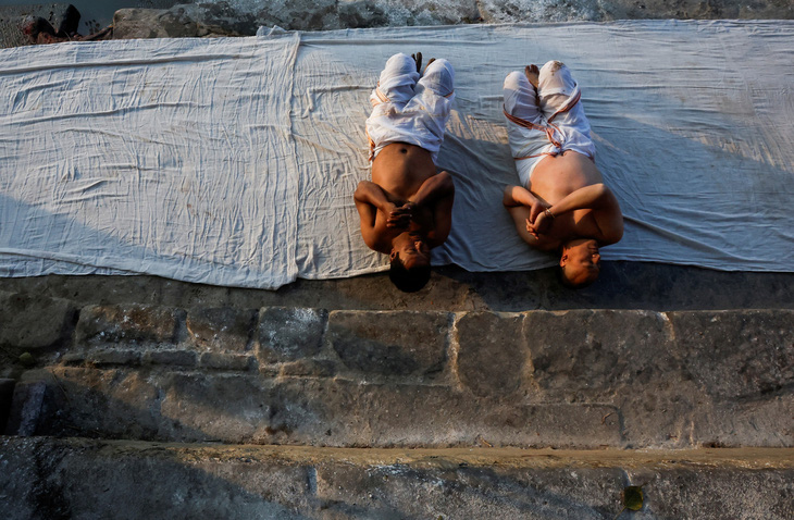 Hai tín đồ cầu nguyện bằng cách cuộn mình nằm dưới đất ở bờ sông Hanumante, thành phố Bhaktapur (Nepal) ngày 29-1. Hoạt động tâm linh này thuộc lễ hội Swasthani Brata Katha - Ảnh: REUTERS