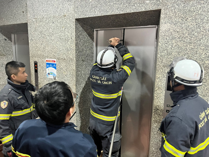 Cảnh sát tạo khe hở để đưa nạn nhân mắc kẹt trong thang máy có thể thoát ra - Ảnh: Công an cung cấp