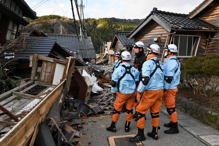 Lính cứu hỏa kiểm tra những ngôi nhà gỗ bị sập ở Wajima, tỉnh Ishikawa - Ảnh: AFP