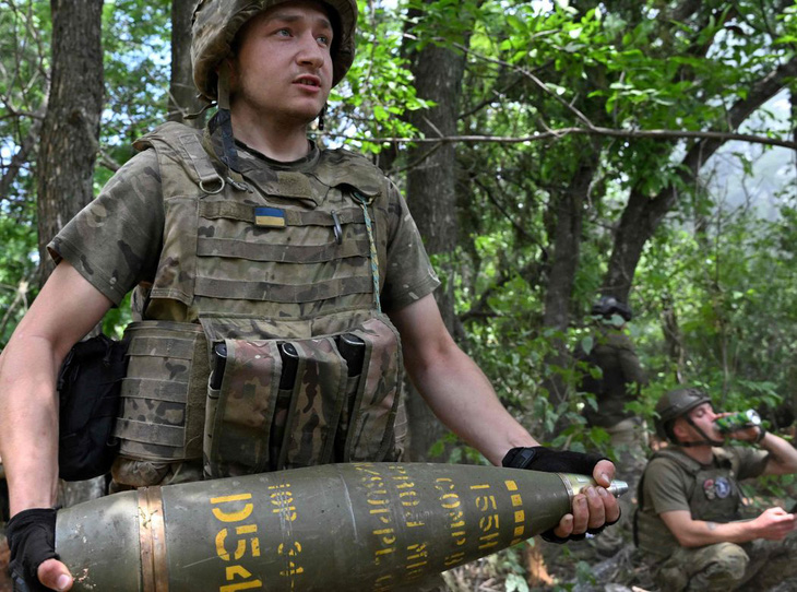 Một người lính Ukraine bê đạn cho khẩu lựu pháo M777 ở Donetsk, phía Ukraine - Ảnh: WALL STREET JOURNAL