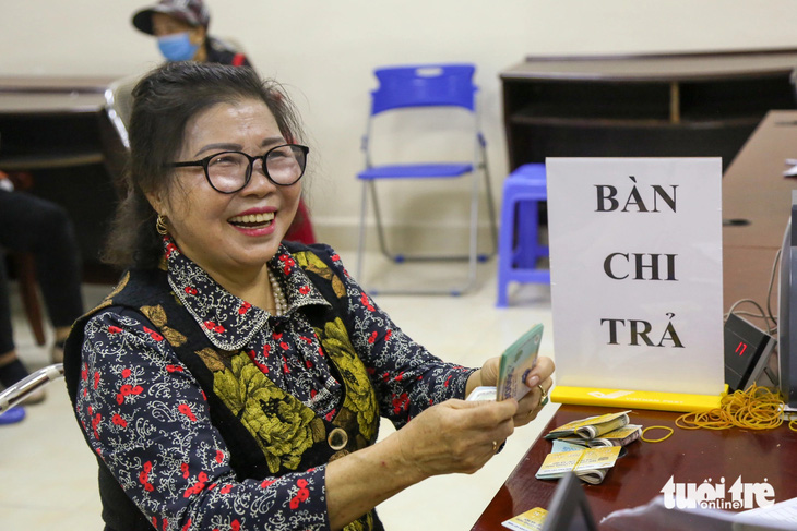 Cô Ứng Thị Minh Phóng, 70 tuổi, ngụ thị trấn Văn Điển, Hà Nội, phấn khởi khi nhận tiền lương hưu gộp hai tháng và quà Tết trị giá 300.000 đồng từ ngân sách - Ảnh: HÀ QUÂN