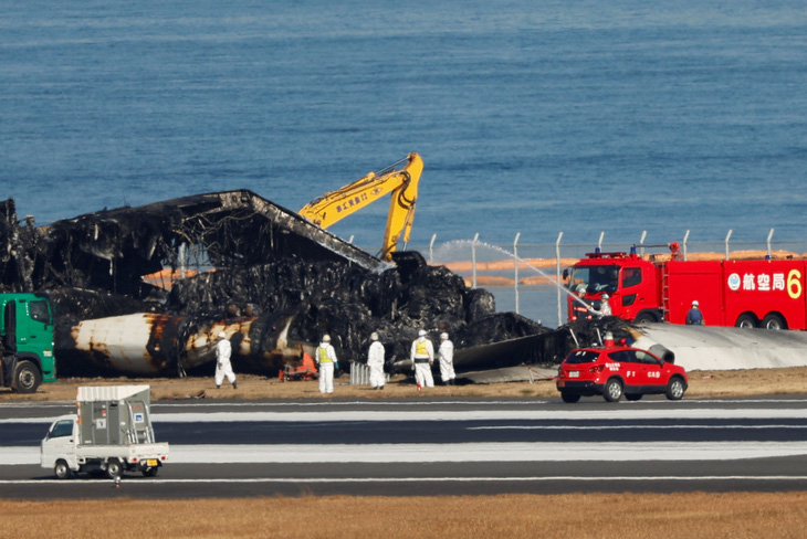 Sáng 5-1, các chuyên gia, công nhân Nhật Bản bắt đầu dọn dẹp hiện trường vụ tai nạn máy bay hôm 2-1 - Ảnh: REUTERS