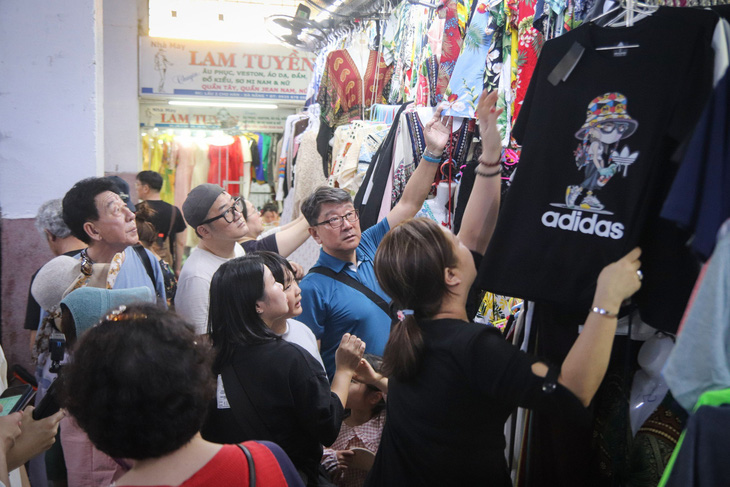 Nhóm du khách Hàn Quốc chọn lựa cho mình những chiếc áo phù hợp với thời tiết Đà Nẵng tại chợ Hàn - Ảnh: THANH NGUYÊN