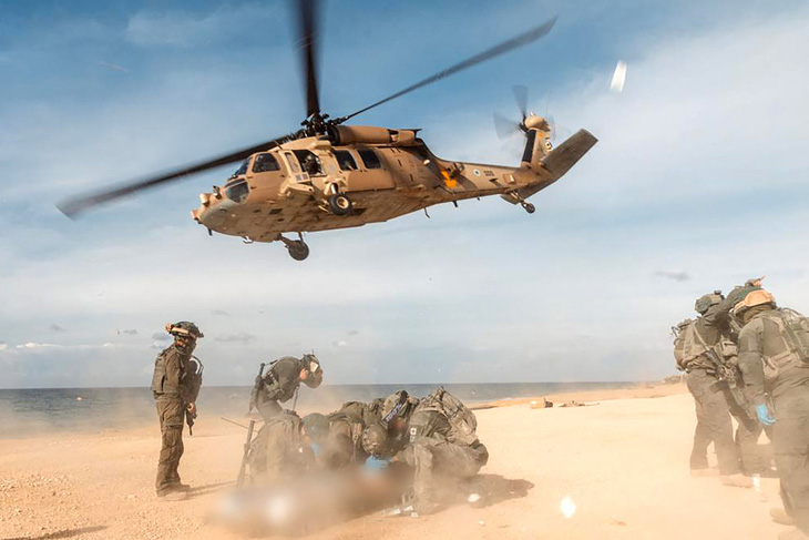Thành viên Đơn vị 669 của Không quân Israel chuẩn bị cho một binh sĩ sơ tán tại bãi biển ở Dải Gaza, ngày 4-1-2024 - Ảnh: AFP