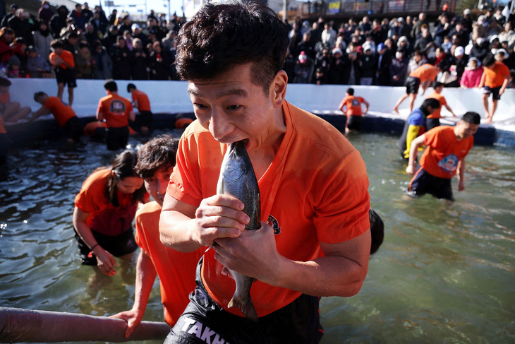 Người đàn ông Hàn Quốc giả vờ ăn con cá mà anh bắt được bằng tay từ một hồ nước đóng băng. Hoạt động này diễn ra hôm 6-1, trong sự kiện quảng bá lễ hội băng Hwacheon thuộc huyện cùng tên, tọa lạc ở phía nam khu phi quân sự chia cắt hai miền Triều Tiên - Ảnh: REUTERS