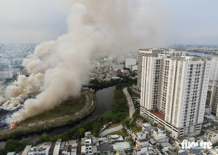 Đám cháy cỏ khiến cột khói bốc cao hàng chục mét gần chung cư - Ảnh: CHÂU TUẤN