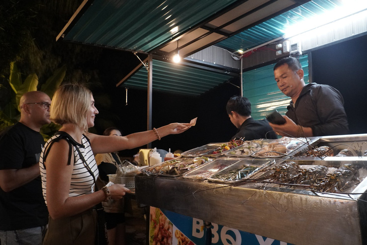 Du khách nước ngoài thưởng thức hải sản nướng tại chợ đêm - Ảnh: Th.Đ.