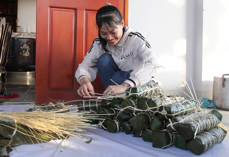 Chị Lê Thị Thùy Dung từ TP Quảng Ngãi lên xã Nghĩa Trung, huyện Tư Nghĩa gói bánh tét tặng bà con thôn Nước Đang - Ảnh: TRẦN MAI