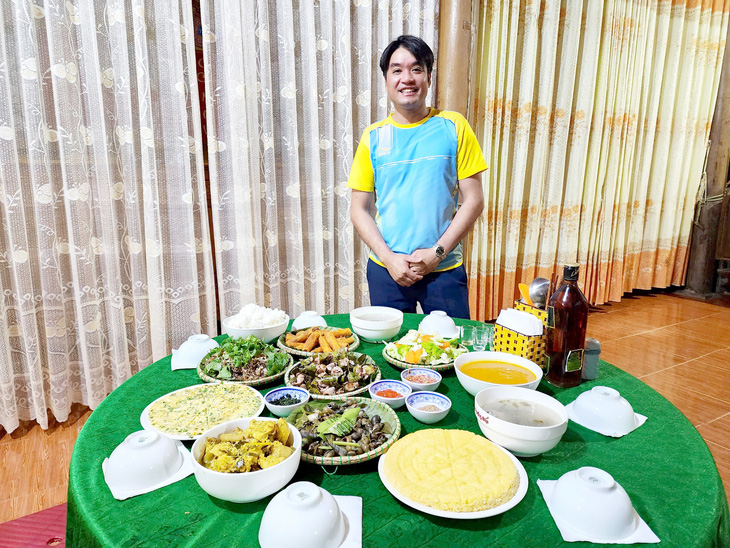 Anh Cao Văn Tin bên mâm cơm đãi khách với nhiều món ẩm thực người Nguồn - Ảnh: THÁI LỘC