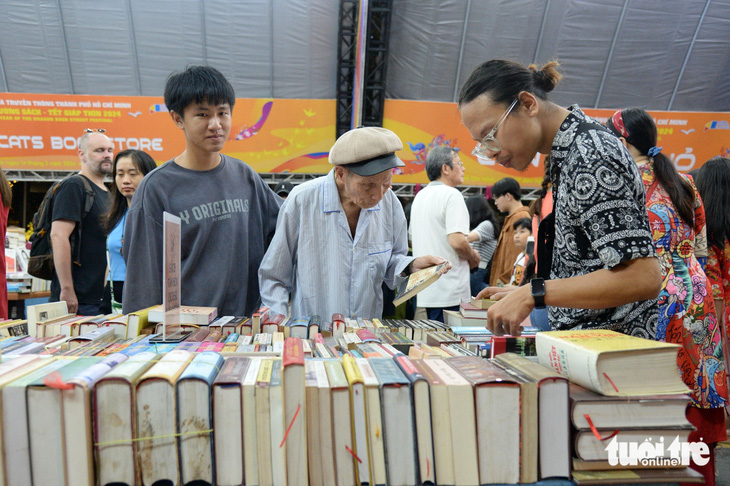 Cụ ông Nguyễn Văn Báu cùng cháu nội Nghĩa Huy (bên trái) mân mê từng cuốn sách - Ảnh: TỰ TRUNG