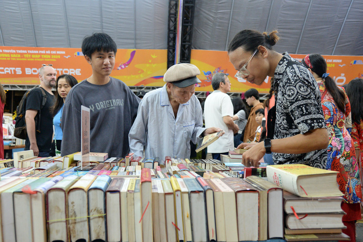 Cụ ông Nguyễn Văn Báu cùng cháu nội mâm mê từng cuốn sách - Ảnh: TỰ TRUNG