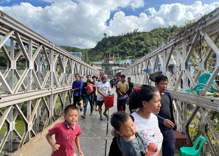 Người dân chạy trốn khỏi Myanmar để tránh xung đột. Họ mang theo đồ đạc đi qua cây cầu nối Myanmar và Ấn Độ tại bang Mizoram, phía Đông Bắc Ấn Độ - Ảnh: REUTERS