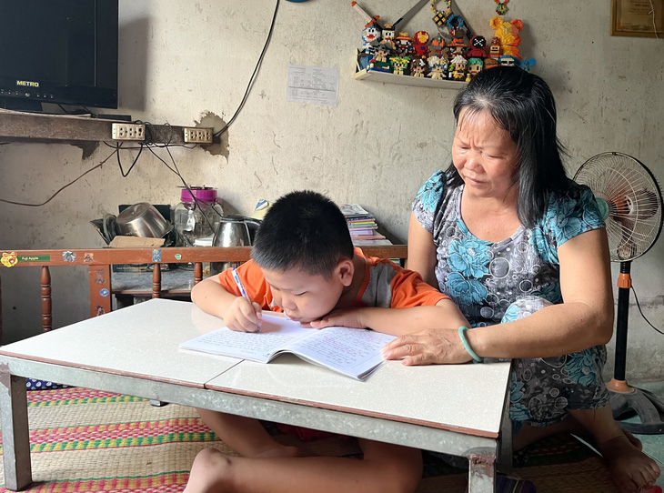 Bé Minh Hưng siêng năng rèn chữ viết mỗi ngày dù bé viết chậm do tay bị hạn chế khả năng vận động - Ảnh: LAN NGỌC