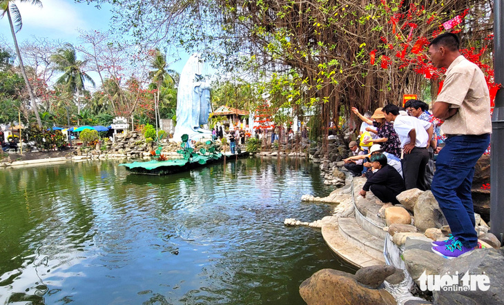 Nhiều người dân, phật tử cho cá ăn vào đầu năm mới ở chùa Thanh Lương - Ảnh: NGUYỄN HOÀNG