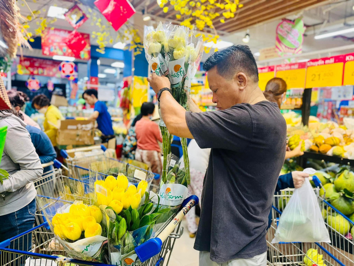 Người dân mua sắm hoa tươi, các siêu thị đảm bảo nguồn hàng tươi sống ngay đầu năm mới. - Ảnh: M.T.