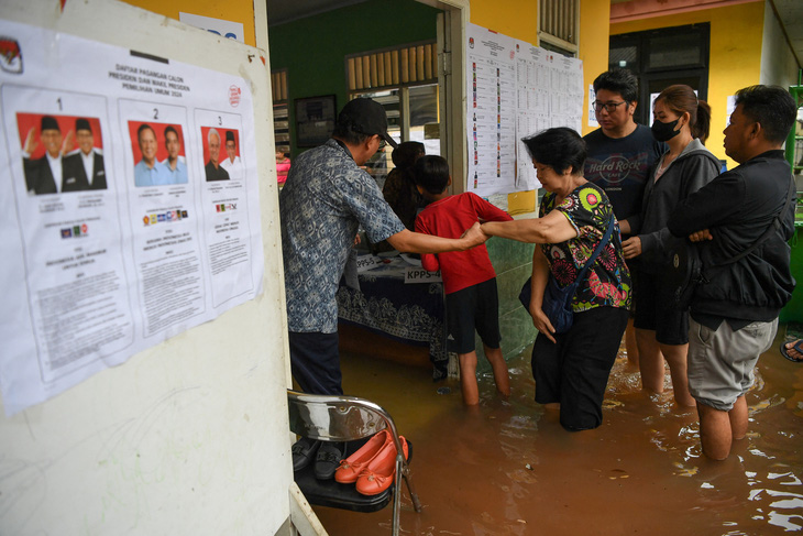 Người dân lội nước đi bỏ phiếu tại Jakarta - Ảnh: REUTERS